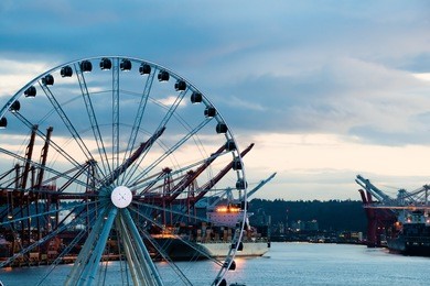 port of seattle with sea going cargo ships and great ferris wheel at twilight. copy space.