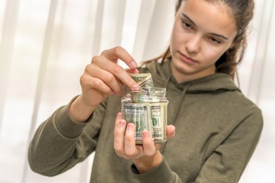 teen girl draws her savings money from glass jars