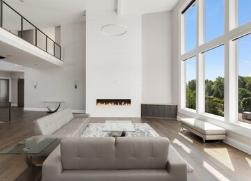 beautiful living room in new luxury home with large bank of windows showing exterior view. 