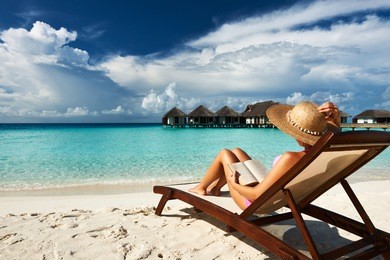 young woman reading a book at the beach