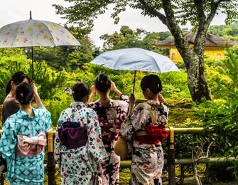 japanese tourists dressed in traditional kimono dresses visiting kinkaku-ji, the golden pavilion, zen buddhist temple,  kyoto, japan.