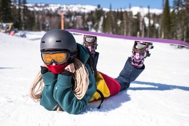 woman snowboarder lying on a snowy slope.