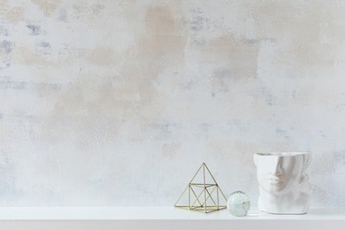 modern and eclectic room interior with abstract wiped walls, gold pyramid and head sculpture .stylish space with design accessories. eclectic home decor. real photo. copy space for inscription.