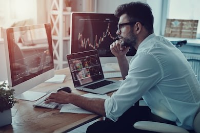 developing new approaches. thoughtful young businessman in formalwear analyzing data using computer while sitting in the office