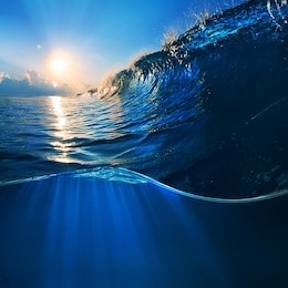 ocaen-view seascape landscape big surfing ocean wave with slightly cloudy sky and the sun
