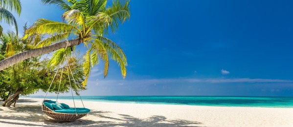 tropical beach panorama as summer landscape with beach swing or hammock and white sand and calm sea for beach banner. perfect beach scene vacation and summer holiday concept. boost up color process
