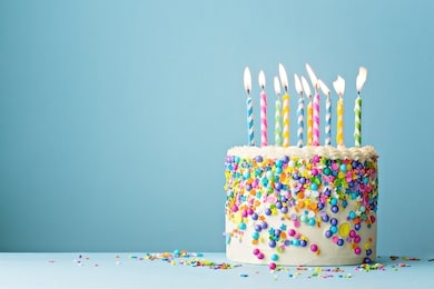 colorful birthday cake with sprinkles and ten candles on a blue background with copyspace