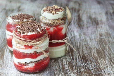 layered dessert with fruits, nuts and cream cheese in glass jar, selective focus