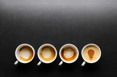 idea. empty and full cups of fresh espresso with bulb sign, view from above