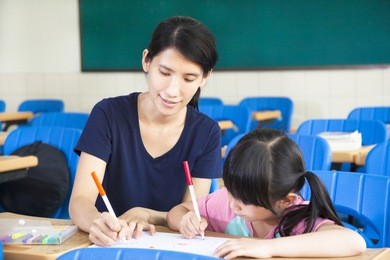 mother teaching little girl drawing picture in the classroom