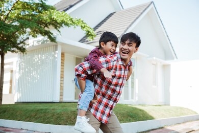 father piggyback ride with his son in front of the house playing enjoying their time in the morning