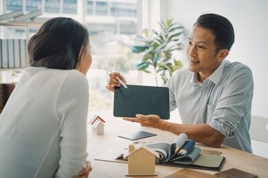 young asian happiness couple love family male and female talking about house purchase discussing a choice with home plan.house design ideas concept with sample material house.