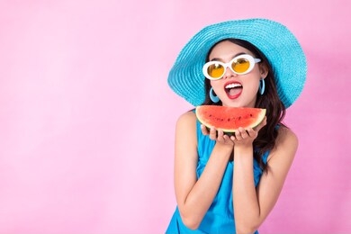 asian woman smiling with watermelon on pink background, summer concept
