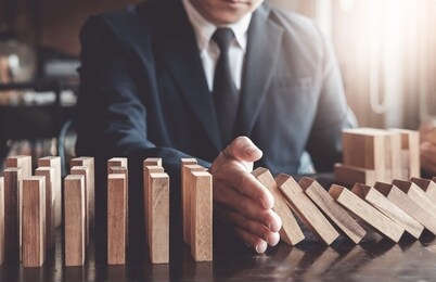 business risk control concept, businessman protect wooden block fall to planning and strategy in risk to business alternative and prevent. investment insurance business.