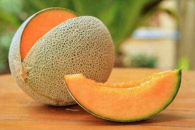 whole and sliced of japanese melons,honey melon or cantaloupe (cucumis melo) on wooden table with blurred garden background.favorite fruit in summer.food,fruits or healthcare concept.