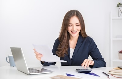 portrait of asian business woman paying bills online with laptop in office. beautiful girl with computer and chequebook, happy paying bills. startup business financial calculate account concept
