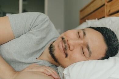 close up asian man sleeping on his bed with happy face. concept of happy dream.