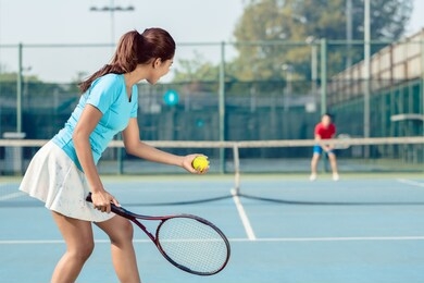 side view of a professional female player smiling while holding the racket and the ball before serving during tennis match