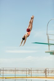 woman diving into the pool from spring board. female diver diving upside down into the swimming pool.