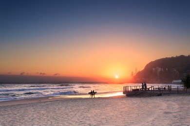 couple surfers walks along the beach in burleigh heads (gold coast, qld, australia)