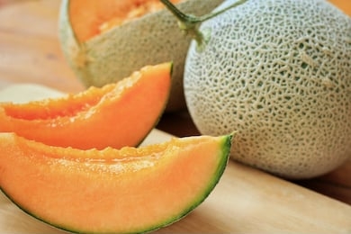 close up at whole and sliced of japanese melons,honey melon or cantaloupe (cucumis melo) on wooden table background.favorite fruit in summer.food,fruits or healthcare concept.