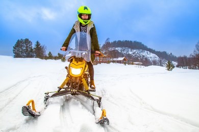girl rides a snowmobile. fun in the winter. sports rest in the winter. yellow snowmobile.