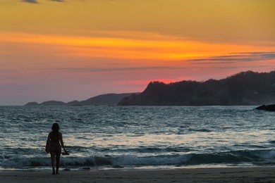一位年轻女性在日落时站在泰国甲米奥南海滩享受假期