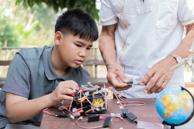 stem education, asian boy and retired grandfather learning programming process of new robot technology. happy family members relationship, studying anywhere anytime to learn together at home outdoor