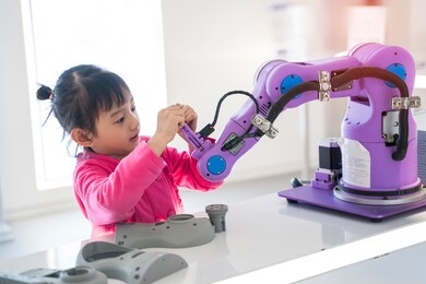 asian little girl touching a robotic machine arm