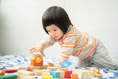 adorable cute beautiful little asian baby girl playing with educational wooden toys healthy happy toddler  colorful wood block indoors at home or nursery,child learning colors and forms family concept