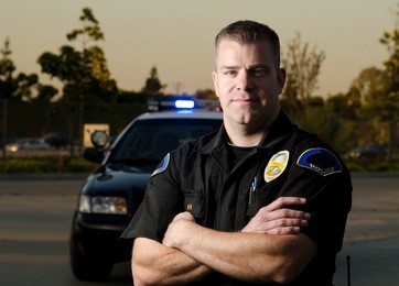 a k9 police officer standing in front of his patrol car with
