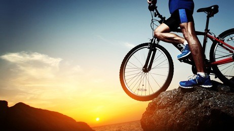 young athlete standing on a rock with bicycle