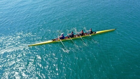 aerial drone bird's eye view photo of yellow sport canoe operated by team of young team in emerald clear sea
