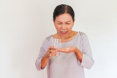 portrait of old asian women hold a glass of water on her hand, feeling difficulty to take medicine.