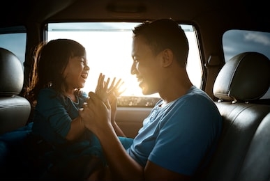 lovely asian daughter with father in the car playing together laughing