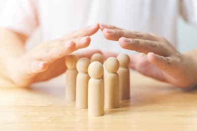 protection people health and insurance concept. hand shield protect wooden human on table