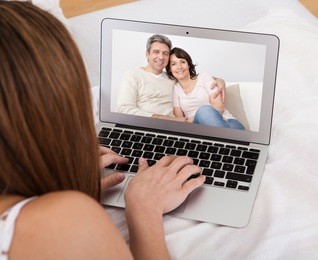 portrait of young woman video chatting with parents