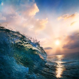 orange sunset on the beach at south summer coast and colorful blue surfing wave closing