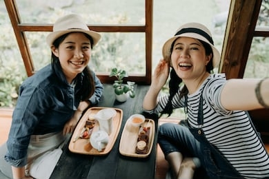 happy japanese friends spending time in tokyo having fun doing tea ceremony drinking eating cake dessert. women tourist taking selfie in wooden traditional house. smiling female making self portrait.