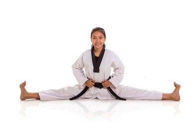 happy girl practicing taekwondo doing split, full body portrait isolated over white background
