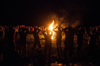 campfire with sparks. group of people dance around big bonfire and sing at the night. party after active day. travel and vacation. great connection to nature concept