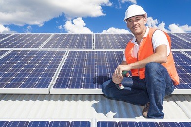 young technician installing solar panels on factory roof