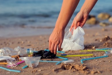hand woman picking up plastic bottle cleaning on the beach. environmental pollution concept