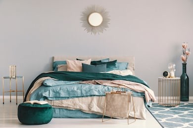 blue, beige and emerald green bedding on king size bed in contemporary bedroom interior with golden accents