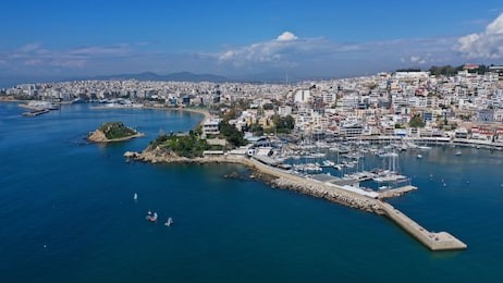 aerial drone bird's eye view panoramic photo of iconic round shaped picturesque port of mikrolimano with sail boats and yachts docked and beautiful clouds, piraeus port, attica, greece