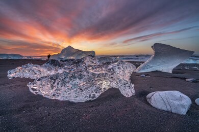 photographers in the background of big pieces of glacial ice on diamond beach near jokulsarlon glacier lagoon in south iceland