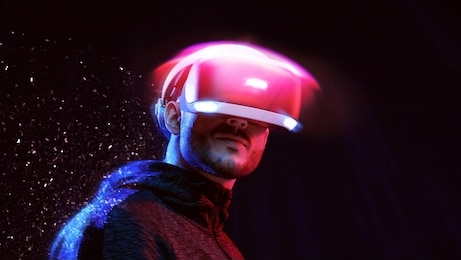 model young man with beard in glasses of virtual reality on dark background. augmented reality, future technology concept. vr. neon light.