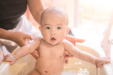 happy baby taking a bath playing with mother washing little girl.mother washing shower happy newborn asian baby in her arms.cute asian newborn baby girl take a bath. 