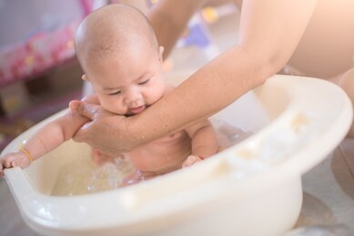 happy baby taking a bath playing with mother washing little girl.mother washing shower happy newborn asian baby in her arms.cute asian newborn baby girl take a bath. 