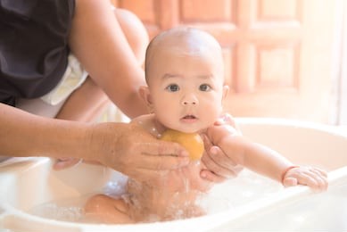 happy baby taking a bath playing with mother washing little girl.mother washing shower happy newborn asian baby in her arms.cute asian newborn baby girl take a bath. 